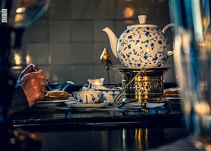 Teekanne mit ostfriesischem Rosenmuster auf einem Stövchen in einem Teehaus auf Juist